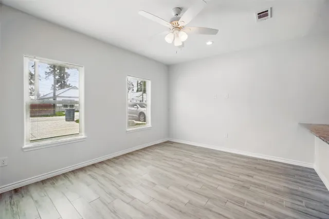 a view of an empty room with a window and wooden floor