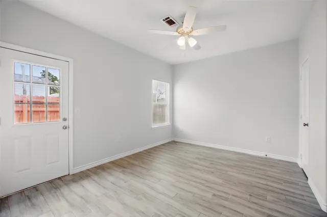 a view of an empty room with wooden floor and a window