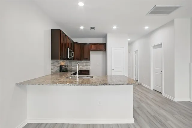 a kitchen with kitchen island granite countertop a sink and refrigerator