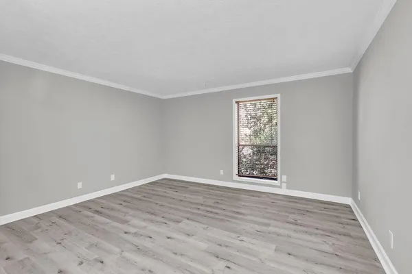 a view of an empty room with window and wooden floor