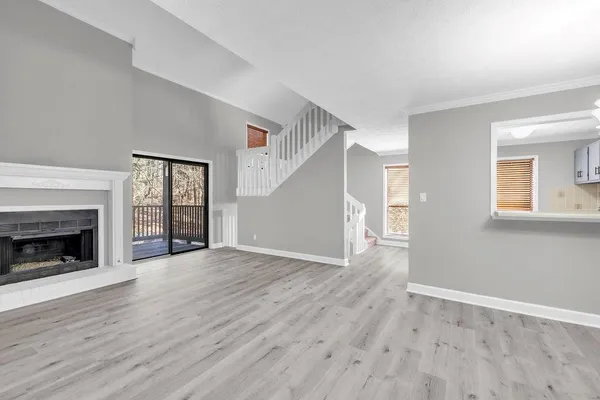 a view of an empty room with wooden floor fireplace and a window