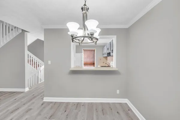 a view of a hallway with wooden floor and chandelier