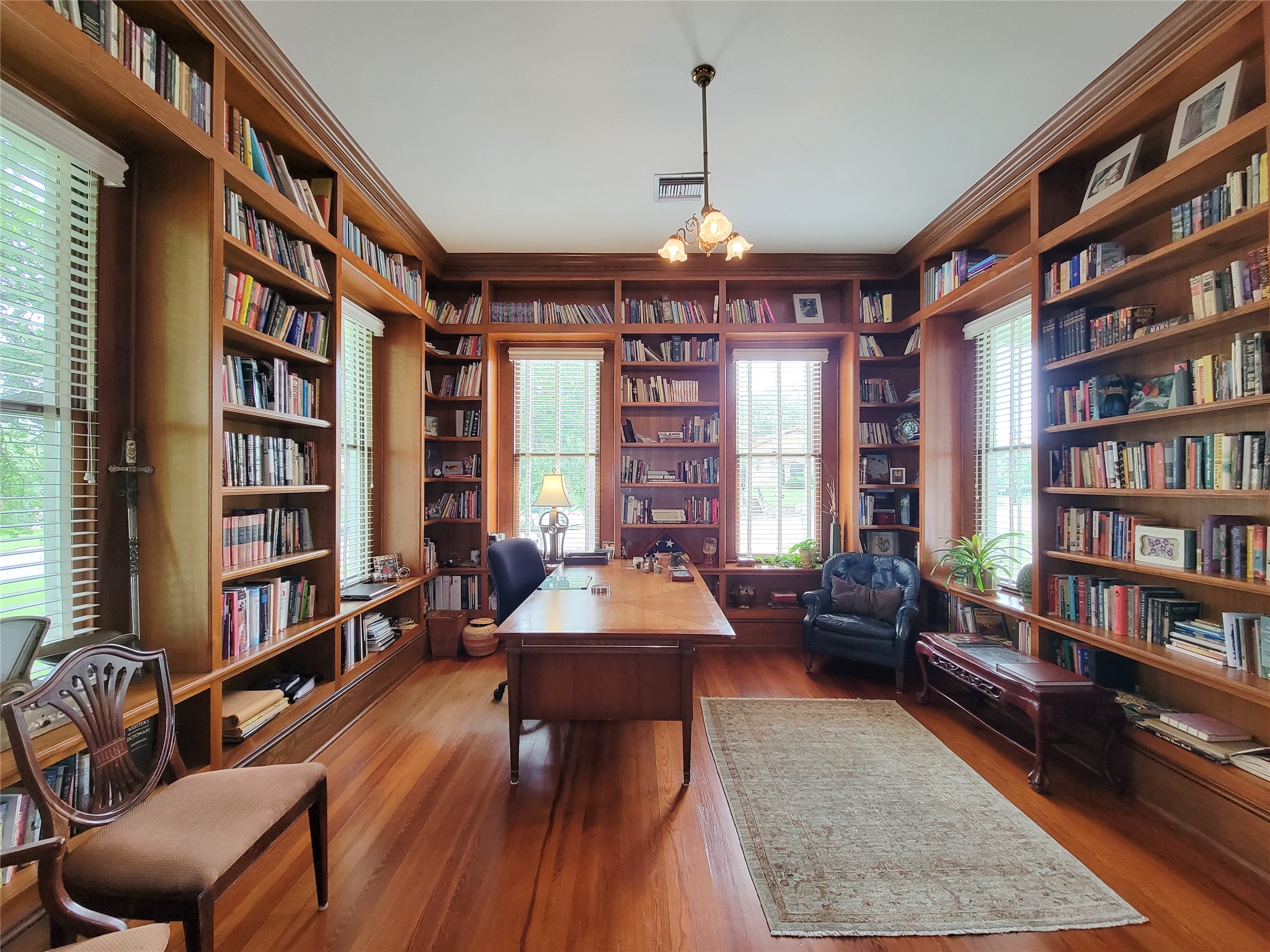 1406 Key Street Brenham, TX 77833 - Photo 7 of 50 Discover a stunning front library featuring extensive solid wood bookshelves, elegant hardwood floors, and an antique chandelier, with pocket doors opening to the dining room.
