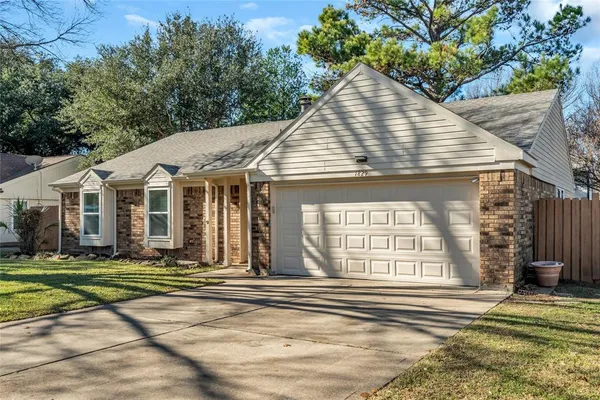 a view of a white house with a small yard plants and large tree