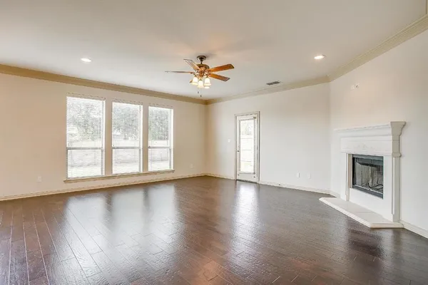 a view of an empty room with a window and wooden floor
