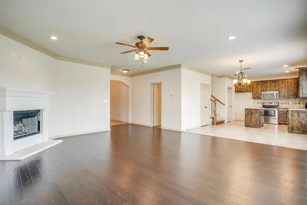 a view of an empty room and kitchen with wooden floor