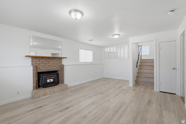 7910 Woolley Way Magna, UT 84044 - Photo 13 of 26 Living area featuring light wood-finish flooring, a brick-front fireplace with a wood mantel, white walls, and recessed lighting