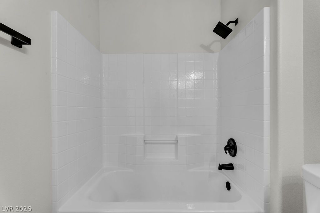 2139 Chapman Ranch Drive Henderson, NV 89012 - Photo 38 of 58 A pristine white tiled shower-tub combination awaits, featuring sleek black fixtures for a contemporary touch.