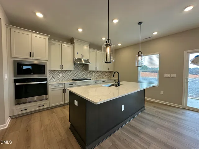 a kitchen with kitchen island granite countertop a sink appliances and cabinets