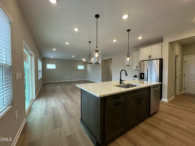 a kitchen with kitchen island a sink appliances wooden floor and a large window