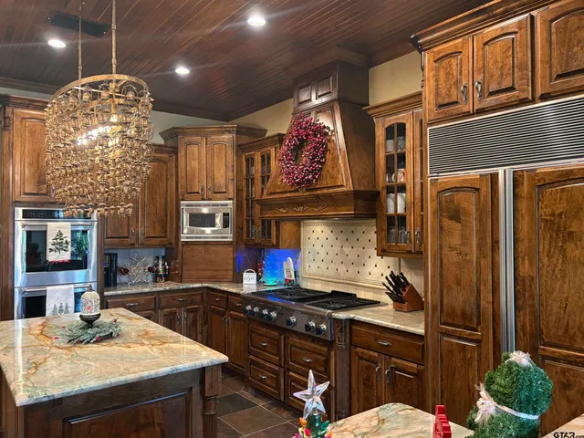 a kitchen with stainless steel appliances granite countertop a stove a refrigerator a sink dishwasher and wooden cabinets with wooden floor