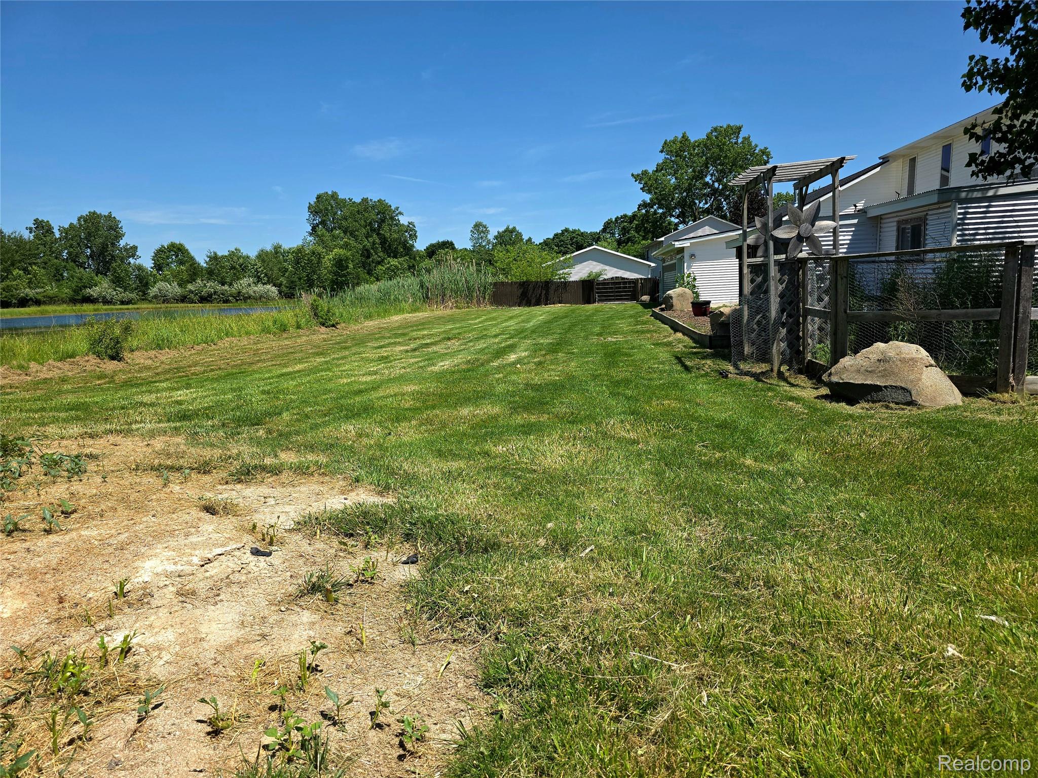 5158 Coldwater Road Columbiaville, MI 48421 - Photo 20 of 25 Expansive outdoor space featuring a large grassy area, mature trees, and a natural water feature