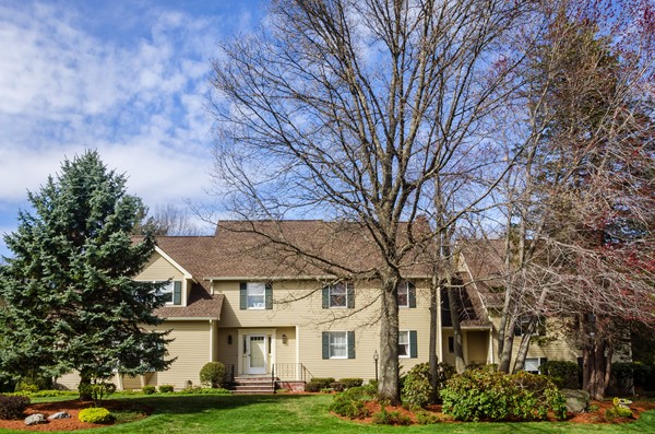a view of a white house next to a yard with large trees