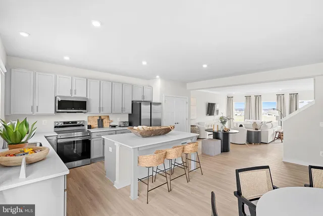 a kitchen with stainless steel appliances kitchen island granite countertop a stove a sink a dining table and chairs