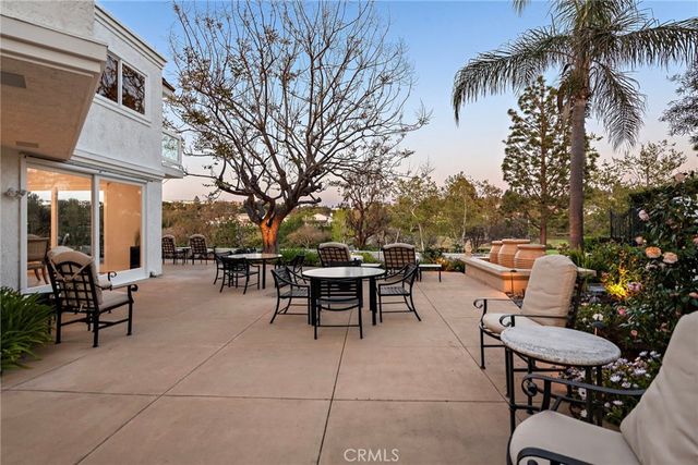 a view of a patio with a dining table and chairs with a fire pit and a large tree