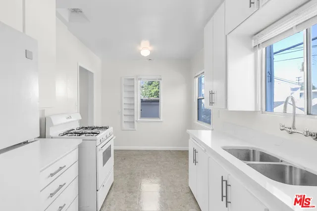 a kitchen with stainless steel appliances a sink stove and white cabinets