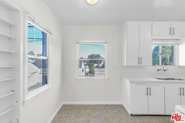 a kitchen with white cabinets and window