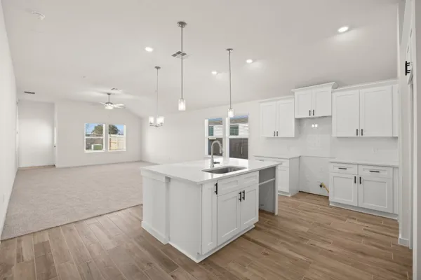 a kitchen with a sink stove cabinets and wooden floor