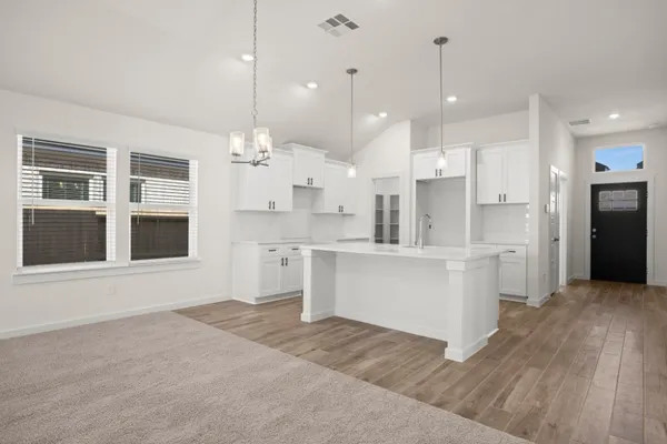 a large white kitchen with kitchen island a refrigerator a stove a sink dishwasher a oven with white cabinets and wooden floor