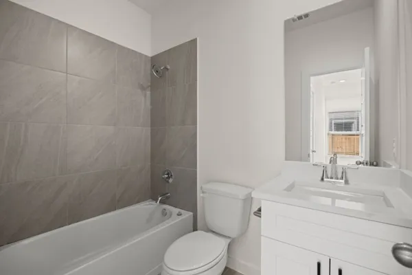 a bathroom with a bathtub shower sink vanity mirror and toilet