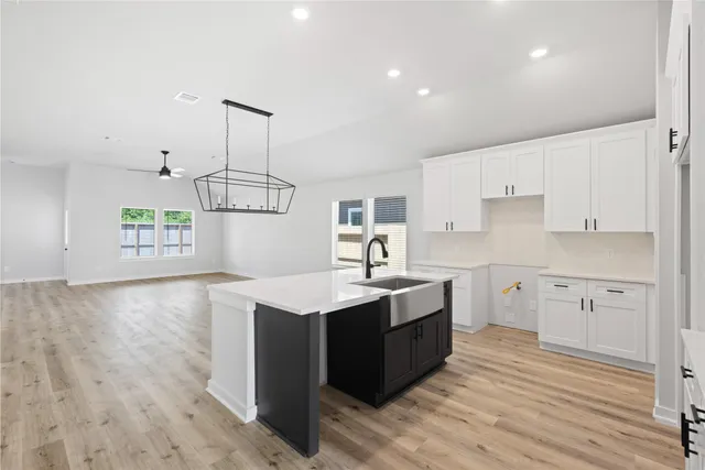a kitchen with a sink a stove cabinets and wooden floor