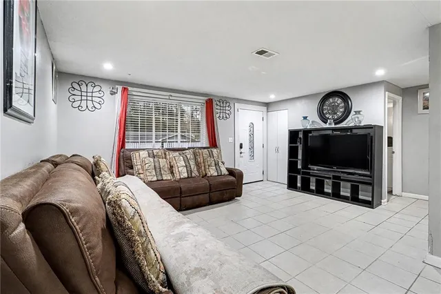 a living room with furniture a flat screen tv and a window