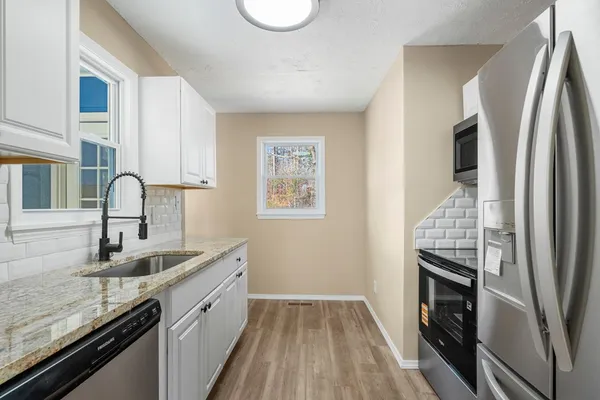 a kitchen with granite countertop a sink and white cabinets