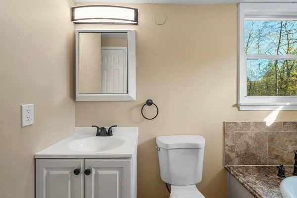 a bathroom with a granite countertop sink a toilet and mirror