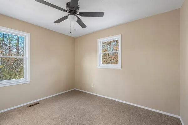 an empty room with a window and a chandelier fan