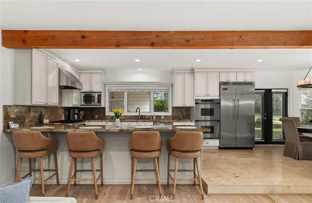 a kitchen with stainless steel appliances granite countertop a table chairs and a refrigerator