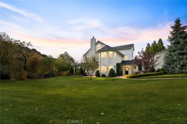 a view of a house with a big yard and large trees