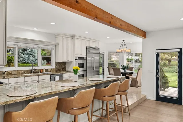 a kitchen with stainless steel appliances kitchen island granite countertop a sink and chairs