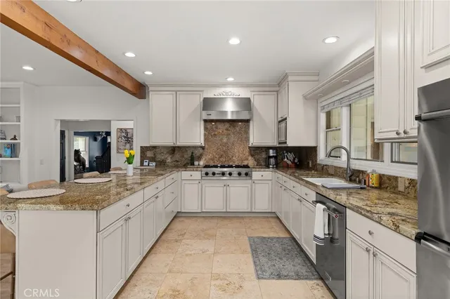 a large white kitchen with stainless steel appliances granite countertop lots of counter space and a sink