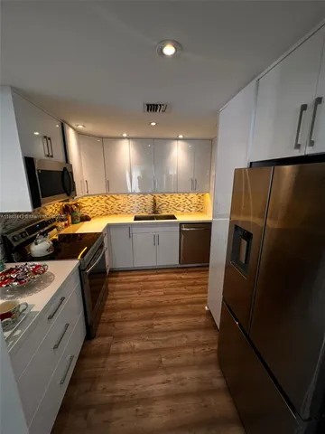 a kitchen with granite countertop a refrigerator stove and sink
