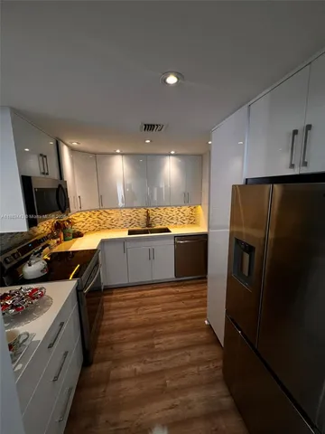 a kitchen with stainless steel appliances granite countertop a refrigerator a sink and a stove