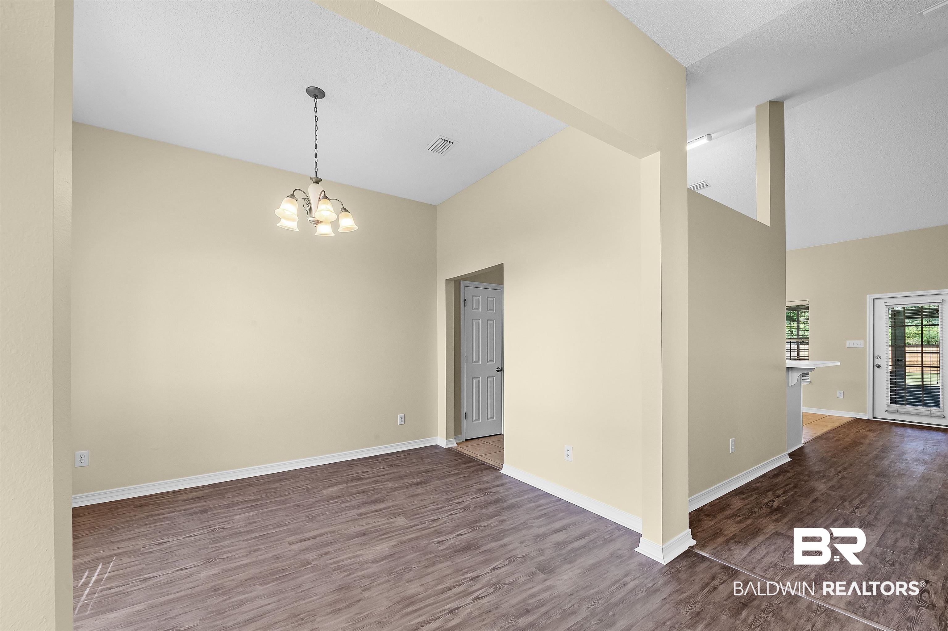 12443 Venice Boulevard Foley, AL 36535 - Photo 20 of 59 Spare room with dark wood-type flooring, vaulted ceiling, and an inviting chandelier