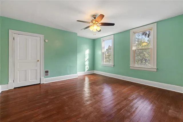a view of an empty room with window and wooden floor