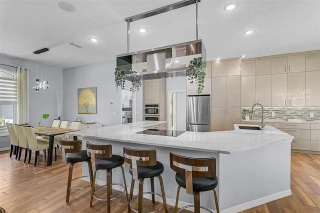a kitchen with stainless steel appliances kitchen island granite countertop a dining table chairs and white cabinets