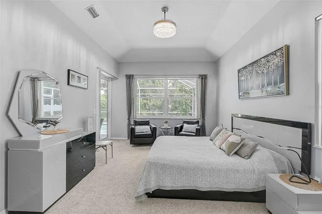 a bedroom with a bed a large window with table and chairs