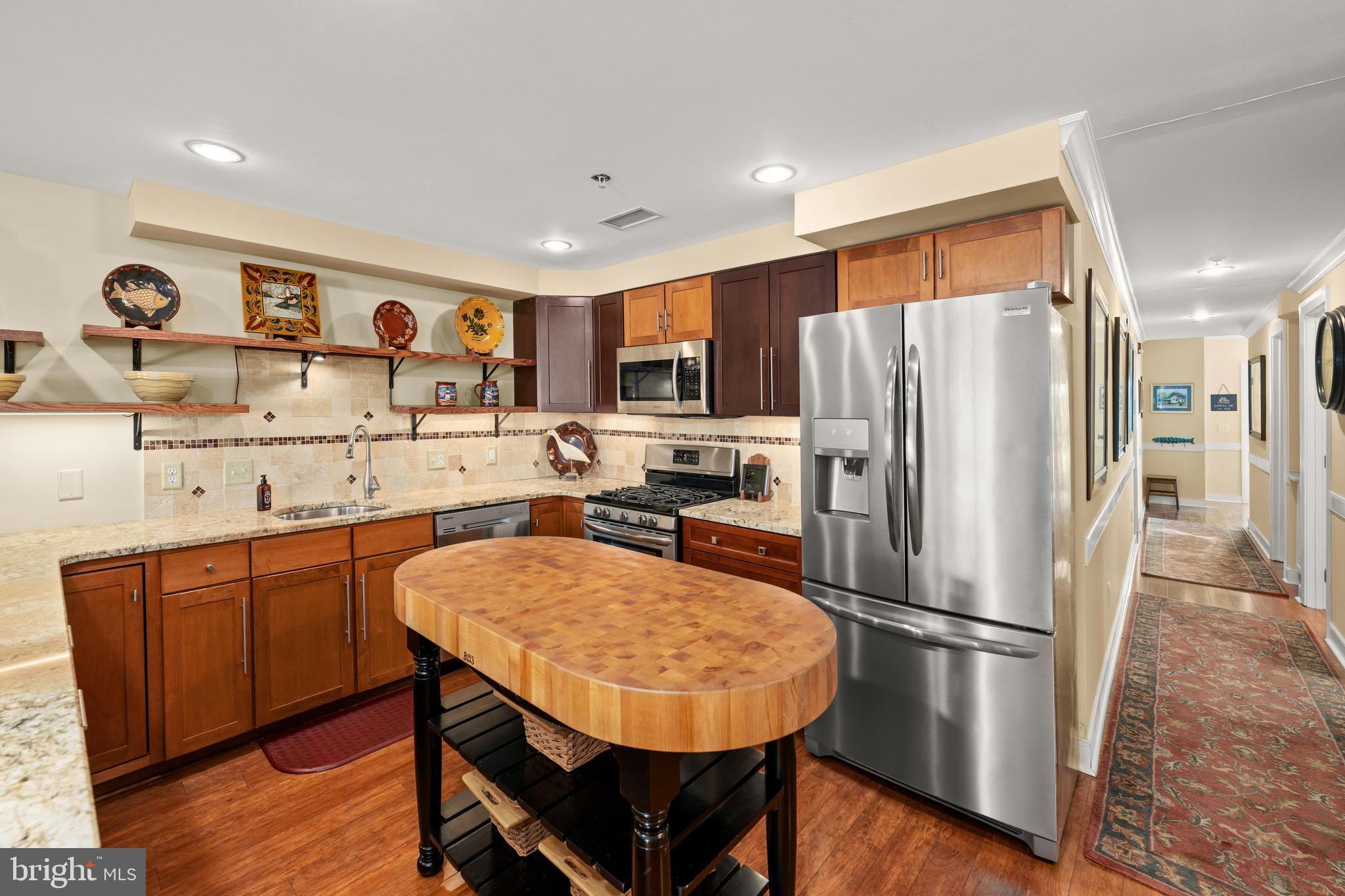 110 Anglers Road, Unit 206 Lewes, DE 19958 - Photo 11 of 40 a kitchen with stainless steel appliances a refrigerator a stove a sink a dining table and chairs with wooden floor