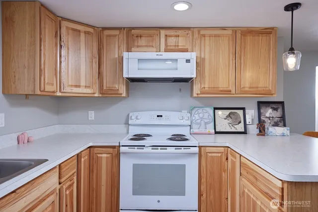 a kitchen with granite countertop a stove a sink dishwasher and cabinets with wooden floor