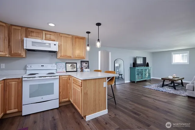 a kitchen with stainless steel appliances granite countertop a stove a sink dishwasher and a refrigerator with wooden floor