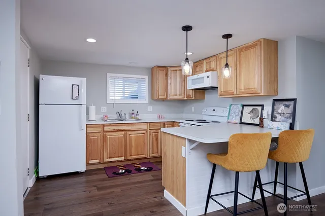 a kitchen with stainless steel appliances granite countertop a refrigerator a sink dishwasher a stove and white countertops with wooden floor