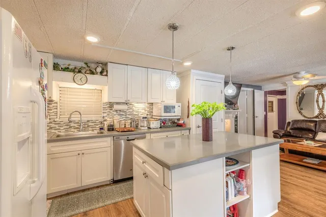 a kitchen with kitchen island granite countertop a sink a counter space appliances and cabinets