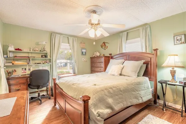 a bedroom with a bed a desk and chair with wooden floor
