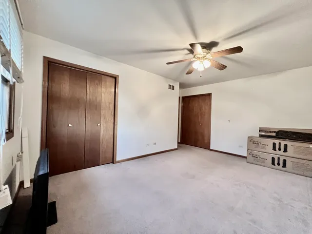 an empty room with ceiling fan and windows