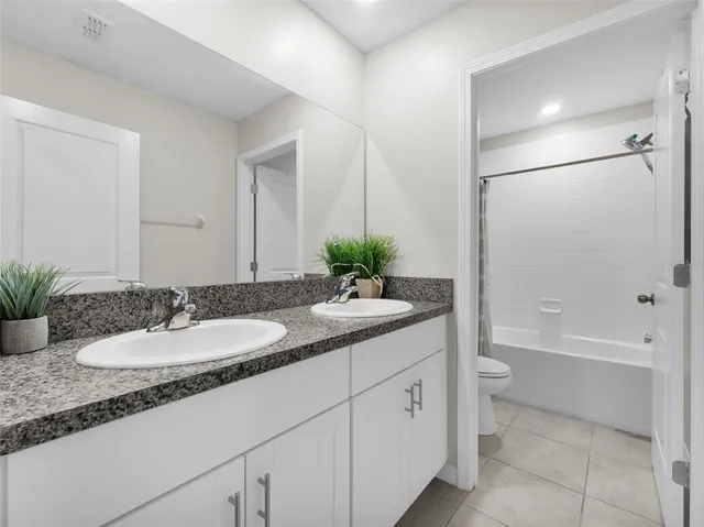 a bathroom with a granite countertop sink a toilet and a bathtub