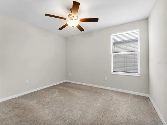 an empty room with a window and a fan