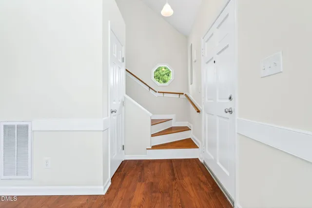 a view of an empty room with wooden floor fireplace and a window
