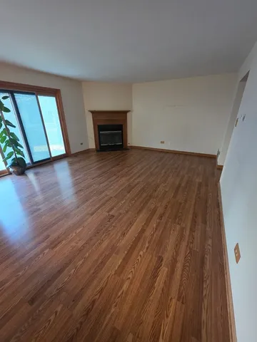 a view of empty room with wooden floor and fireplace